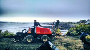 man operating trenching equipment near ocean