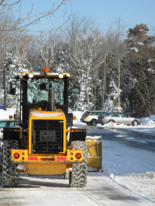 bucket loader clearing snow from parking lot