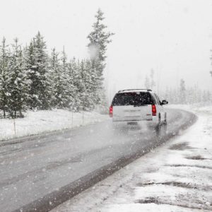 SUV driving on snowy road during snow storm